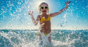 Girl playing in water with the sun directly behind her