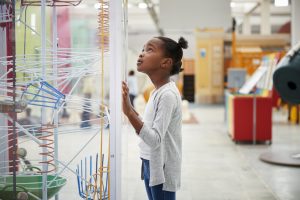 Young black girl looking at a science exhibit, close up