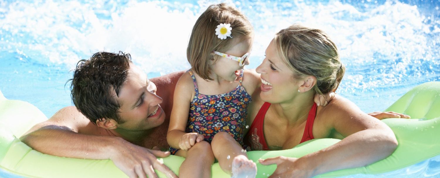 Family On Holiday In Swimming Pool Smiling And Laughing.