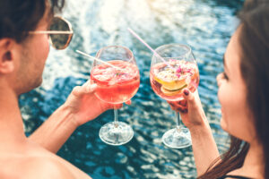 Young man and woman together in the swimming pool drink